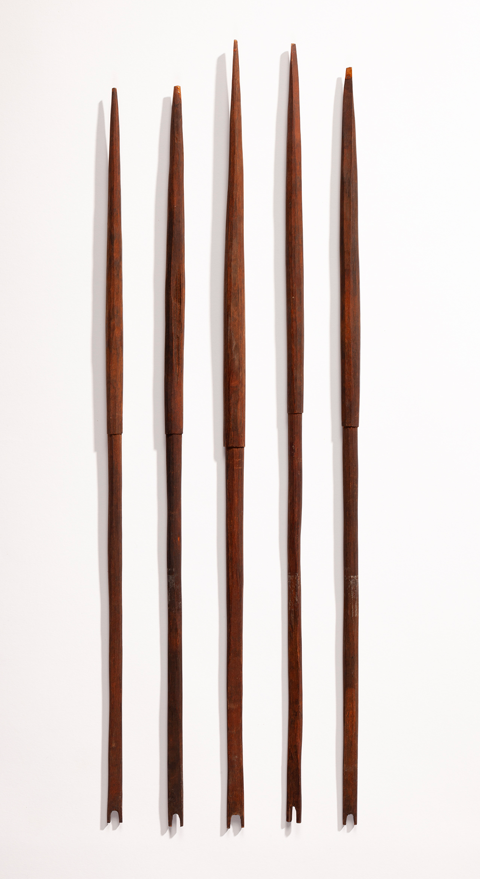 A set of five thin wooden arrows lined up next to each other vertically.