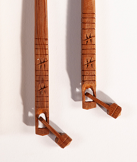 A closeup of the carved ends of the wooden chopsticks and the tiny bell shapes attached.