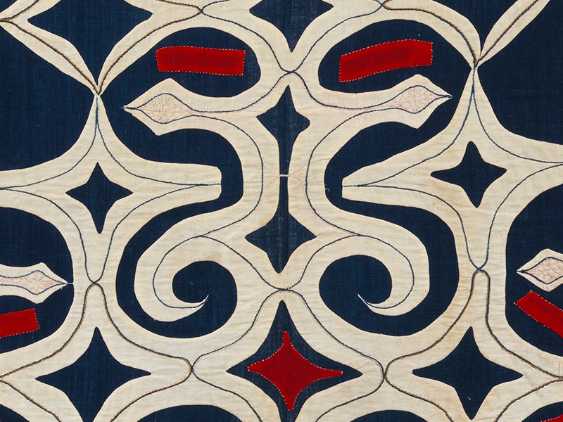 A closeup of a geometric Ainu pattern in blue and red and white.