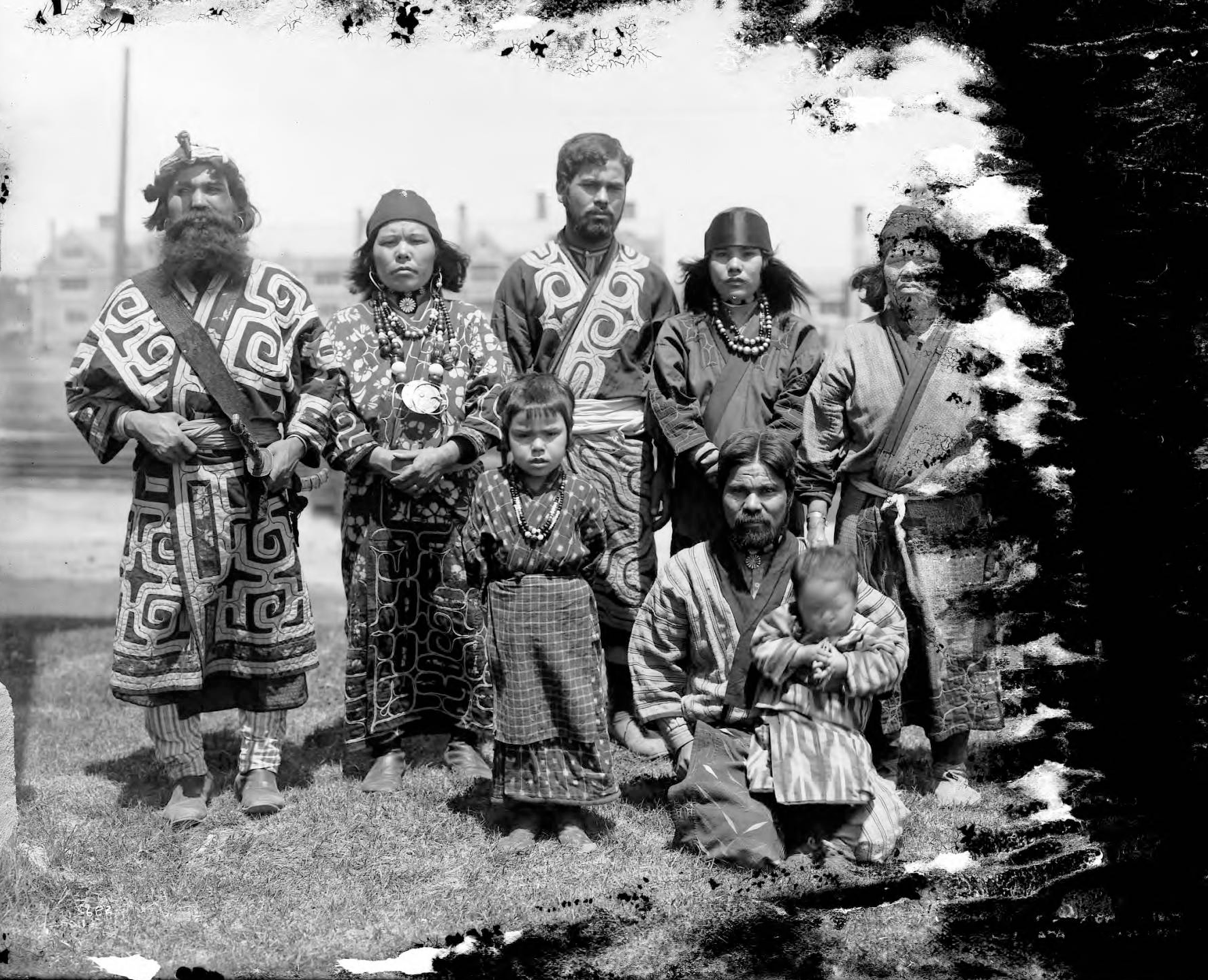 A black and white photograph of an Ainu family in traditional clothing.