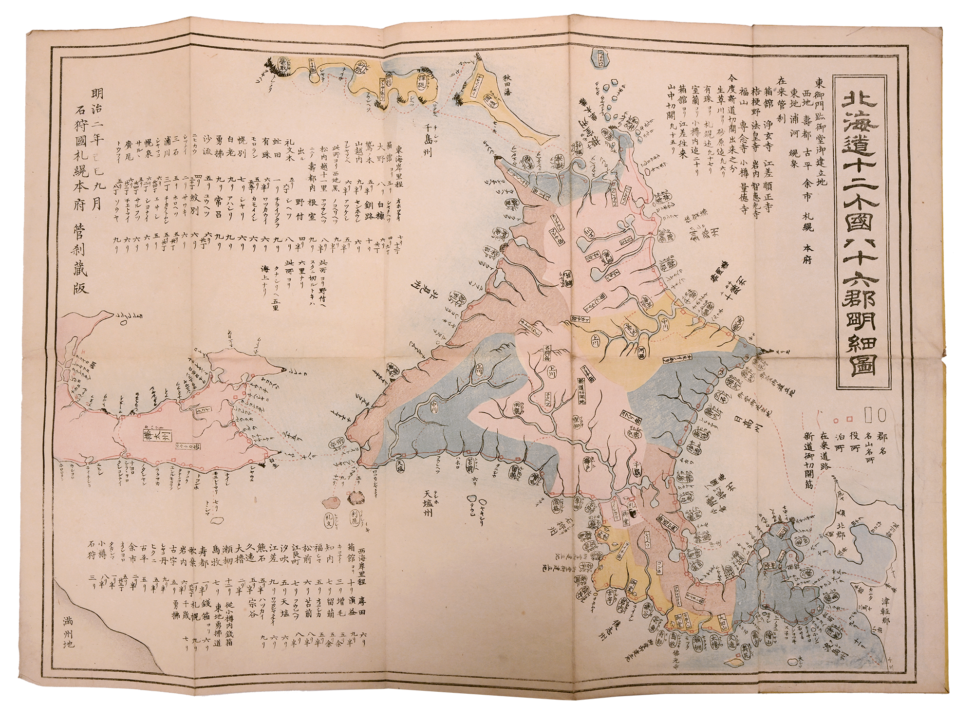 A printed map of Hokkaido, colored in soft shades of pink, blue, and yellow, with labels on towns and routes and lots of geographic text printed around the map as a guide.