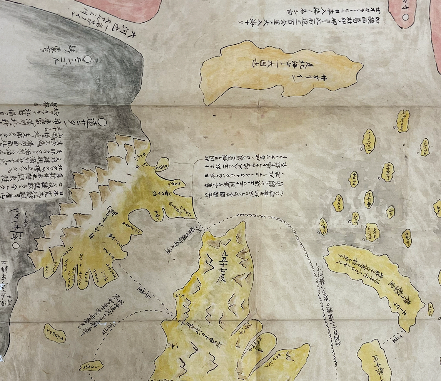 A closeup of Sakhalin on a hand painted map, with the island divided into two parts and in yellow. One part is an island and the other is attached to the mainland.