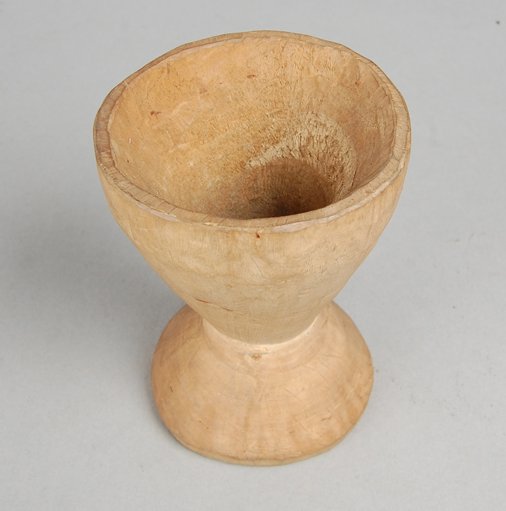 A small wooden mortar of a light brown color.