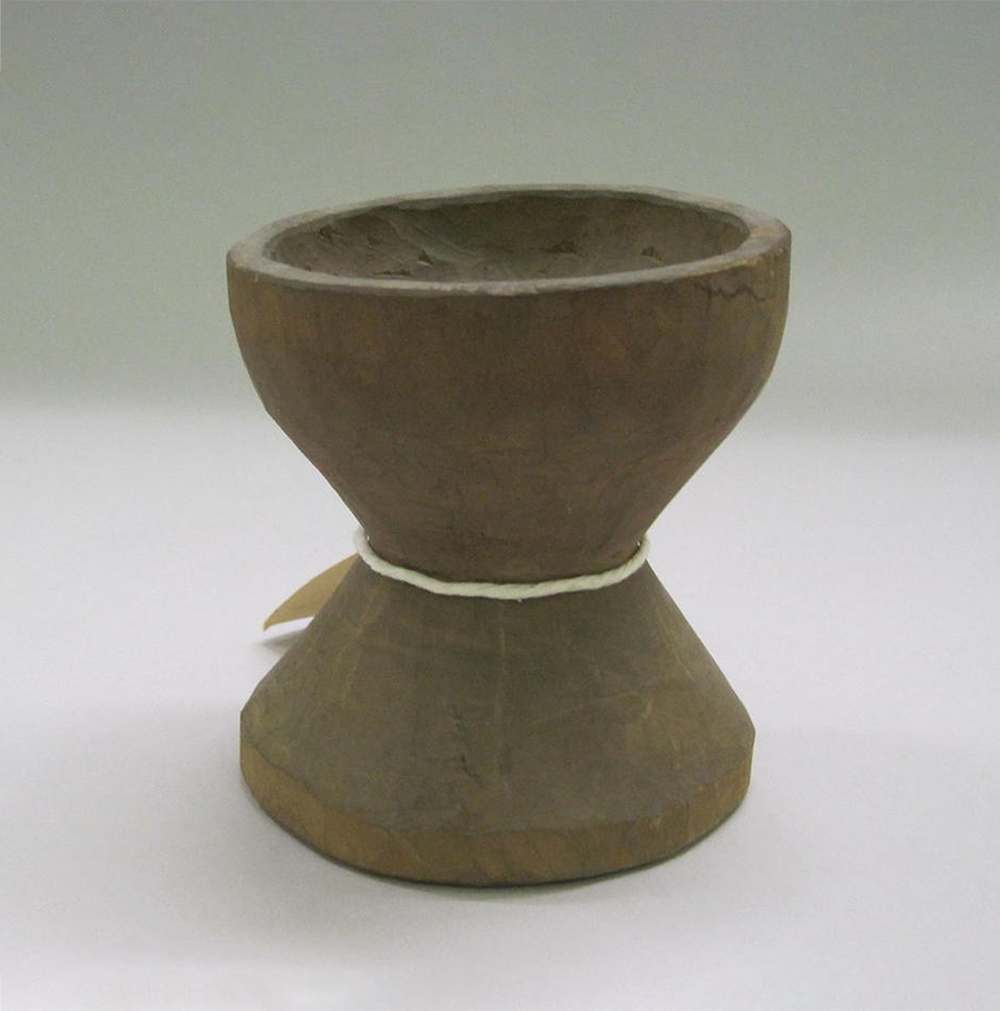 A small wooden mortar of a dark brown color.