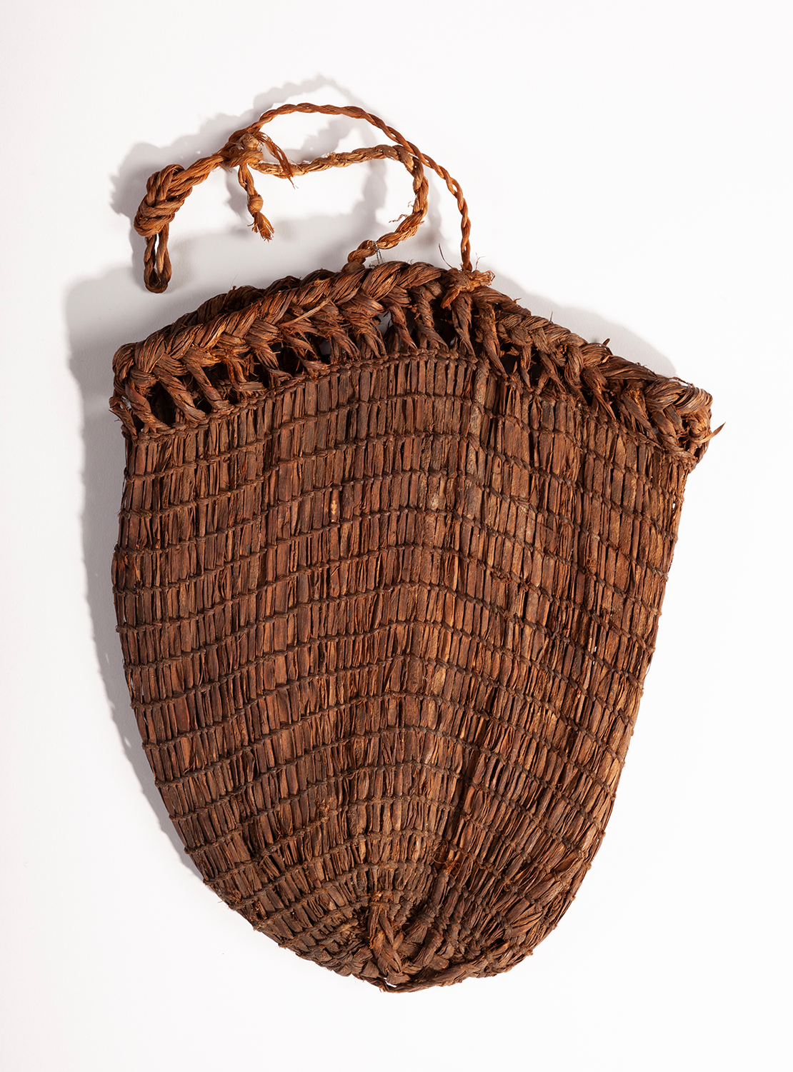 A saranip basket with a round shape made of bark and fibe with tightly woven patterns.