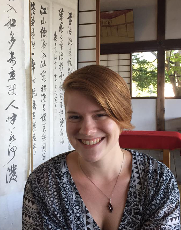 A white woman with reddish blonde hair smiling. She is sitting in a Japanese tea house.